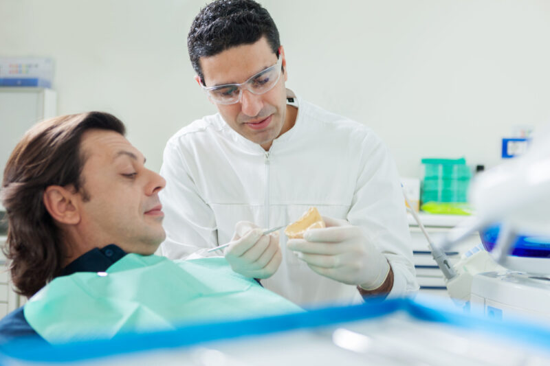 Dentist is showing a plaster model to his patient